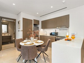A modern kitchen with a dining area, featuring a central island with a sink, a built-in oven, and a microwave. - New 1BR | Burj Khalifa Infinity Pool | Dubai Mall (Dubai)