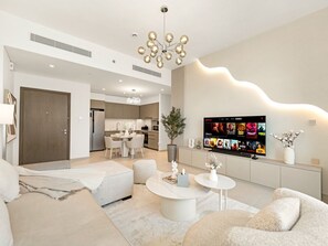 Ein modernes Wohnzimmer mit Flachbildfernseher, Essbereich und einer Küche im Hintergrund.