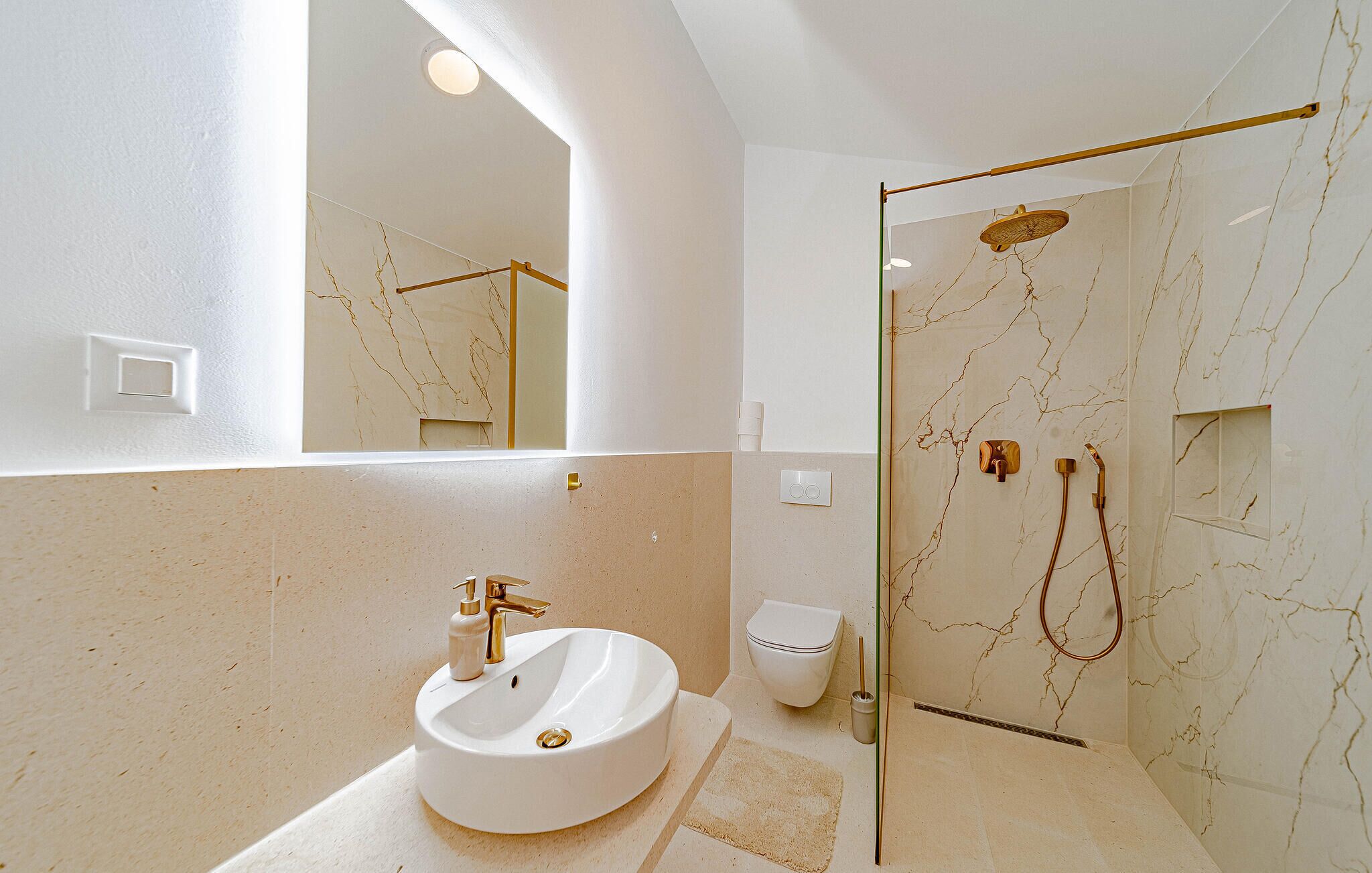 Ein Badezimmer mit einem weißen Waschbecken, einer Toilette und einer Duschkabine mit Handbrause.