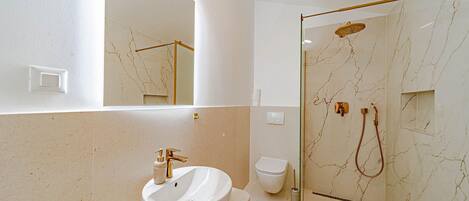 Ein Badezimmer mit einem weißen Waschbecken, einer Toilette und einer Duschkabine mit Handbrause.