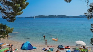 A beach with clear blue water, a tent, and people sunbathing.