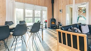 Et hyggeligt værelse med træpaneler, en pejs, et spiseområde med stole og en sofa.