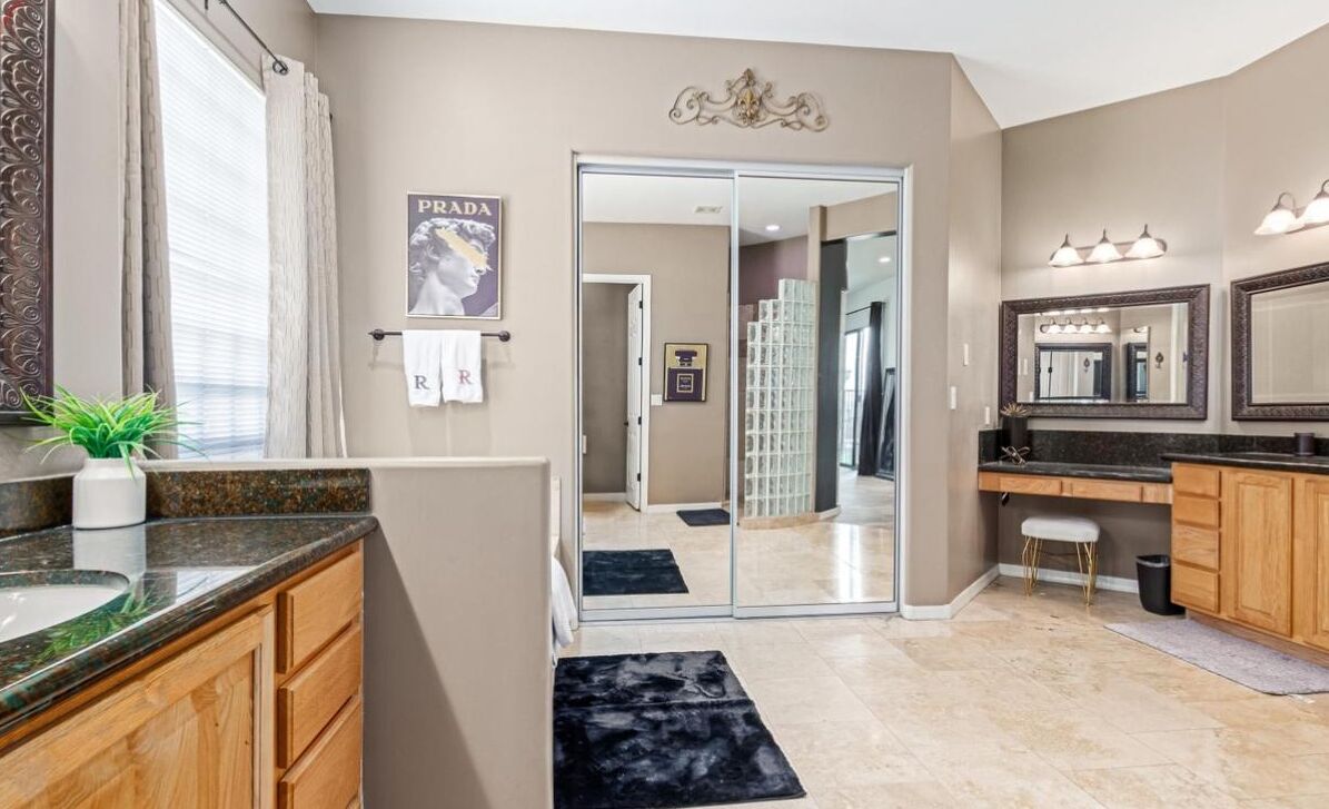 Une salle de bain moderne avec un grand miroir, un meuble-lavabo et un espace douche visible à travers une porte en verre.