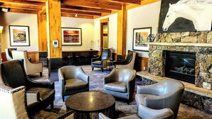 A lobby with leather chairs, a stone fireplace, and framed artwork on the walls.