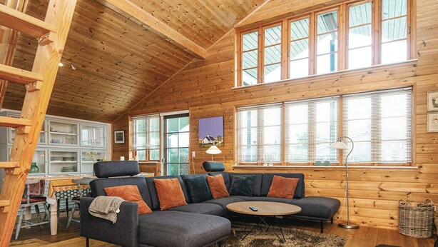 A cozy wooden interior with a sectional sofa, a dining area, and large windows. - 4 Star Holiday Home in Hovborg (Hovborg)