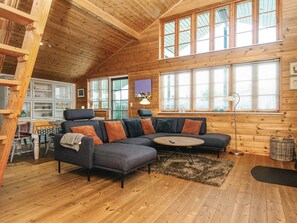 Ein gemütliches Holzinterieur mit einem Ecksofa, einem Essbereich und großen Fenstern.