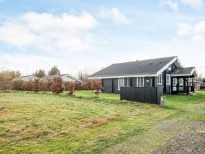 A residential property with a detached house featuring a porch, a fenced yard, and a gravel driveway. - 4 Star Holiday Home in Hovborg (Hovborg)