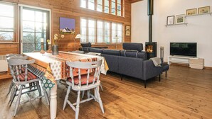 A cozy cabin interior with a dining table, chairs, a sofa, a fireplace, and a TV. - 4 Star Holiday Home in Hovborg (Hovborg)