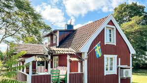 A red wooden house with a balcony, a flag, and a chimney. - 5 Person Holiday Home in Borgholm (Borgholm)