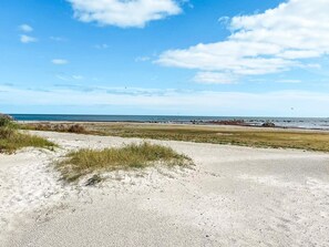 A beach with a clear sky, sandy dunes, and a distant shoreline. - 5 Person Holiday Home in Borgholm (Borgholm)