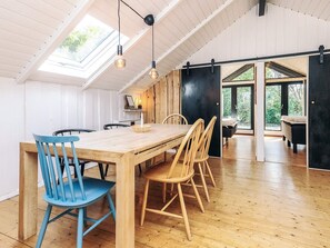 A dining area with a wooden table and chairs, a skylight, and a view of the outdoors. - 4 Star Holiday Home in Vaeggerlose (Vaeggerlose)