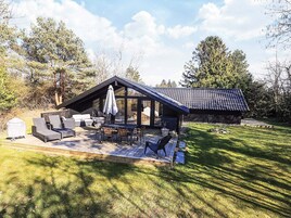 A modern outdoor patio with a dining table and chairs, a covered seating area, and a barbecue grill.