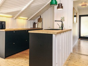A kitchen with a wooden countertop, black cabinets, and a green pendant light. - 4 Star Holiday Home in Vaeggerlose (Vaeggerlose)
