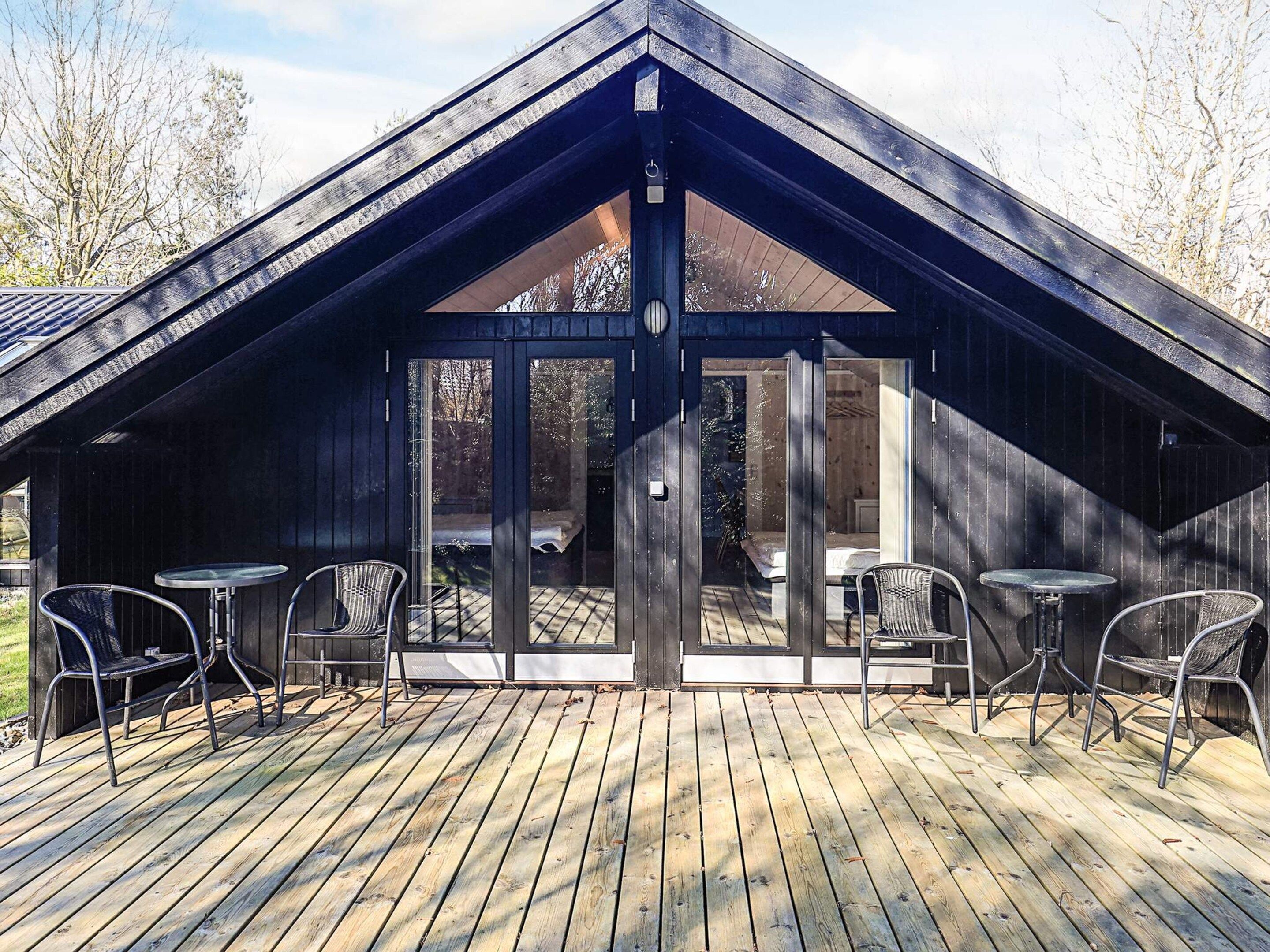 A wooden deck with metal chairs and a glass door leading to an interior space.