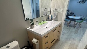 A bathroom with a white toilet, a sink with a mirror above it, and a small potted plant. - Cozy 3BR Suite at Winnipeg South (Winnipeg)