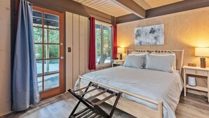 A bedroom with a bed, a nightstand, a wall clock, and a window with curtains. - Relaxing, Private Cabin w/Hot Tub & Generator near Mt Rainier! (Ashford)