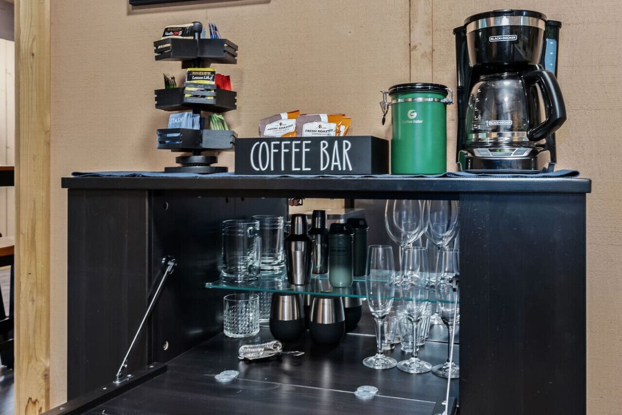 A coffee bar with a coffee maker, a green thermos, and various coffee pods.