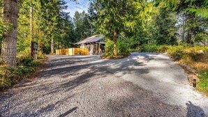 A gravel driveway leading to a cabin surrounded by dense forest. - Relaxing, Private Cabin w/Hot Tub & Generator near Mt Rainier! (Ashford)