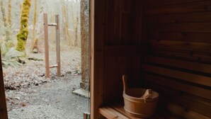 A wooden sauna with a bench and a wooden bucket.