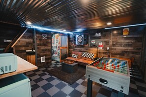 A cozy room with a foosball table, a couch, and a dartboard.