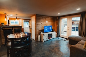 Una habitación acogedora con detalles de madera, televisión, chimenea y un comedor con un tablero de ajedrez.