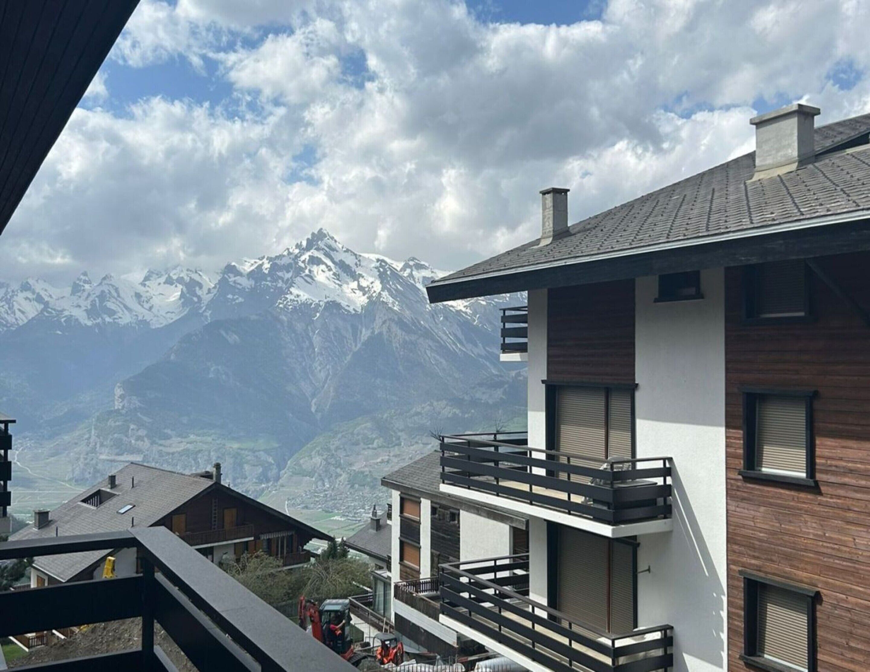 Ein modernes Gebäude mit einem Balkon, der auf eine gebirgige Landschaft blickt.