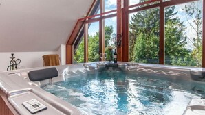 A hot tub with a control panel, a glass of wine, and a bottle of wine on a wooden table. - Comfortable Villa With Facilities (Benecko)