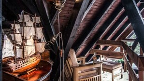 A wooden boat model in a loft with a sloped ceiling, a floor lamp, and a wooden bench. - Comfortable Villa With Facilities (Benecko)