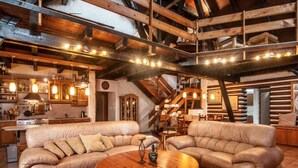 A rustic interior with exposed wooden beams, a kitchen area, and a seating arrangement with a round wooden table. - Comfortable Villa With Facilities (Benecko)
