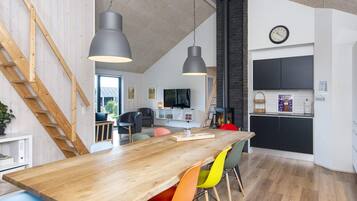 Eine moderne Küche mit einem Holztisch, bunten Stühlen, einem eingebauten Herd und einer Uhr an der Wand.