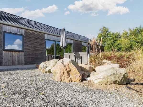 A modern building with large windows, a gravel driveway, and a rock garden.