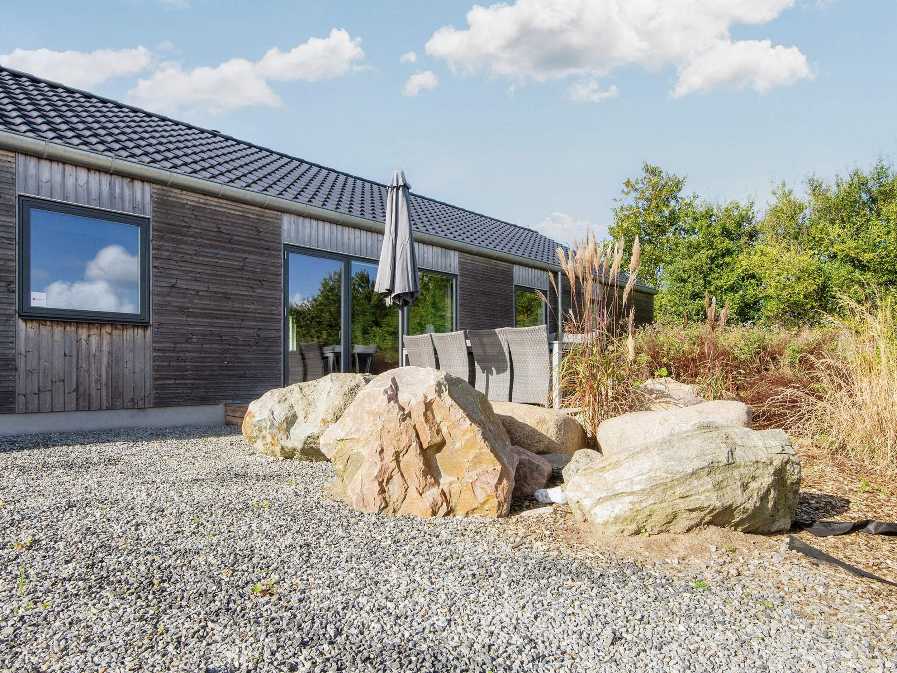 A modern building with a gravel driveway, large rocks, and outdoor seating.