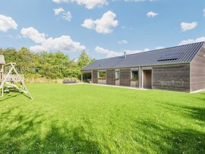 A modern building with a sloped roof, a covered outdoor area, and a grassy lawn. - 4 Star Holiday Home in Sydals (Sydals)