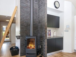 A modern kitchen with a black brick fireplace, wooden flooring, and a clock on the wall. - 4 Star Holiday Home in Sydals (Sydals)
