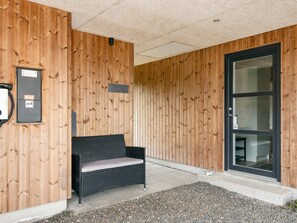 A wooden exterior wall with a bench, a door, and a small sign.