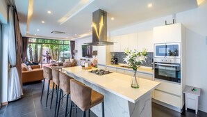 A modern kitchen with a central island, built-in appliances, and a large window.