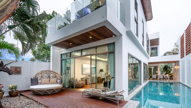 A modern house with a swimming pool, wooden deck, and outdoor seating area.