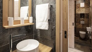 A modern bathroom with a large mirror, a round sink, and a wooden vanity.