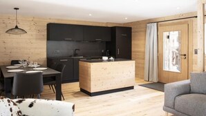 A modern kitchen with black cabinets, a wooden island, and a dining area with a table and chairs.