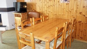 A wooden dining table with six chairs, a leather sofa, and a television on a wooden stand. - Mystical Apartment With Mountain Views (Veysonnaz)