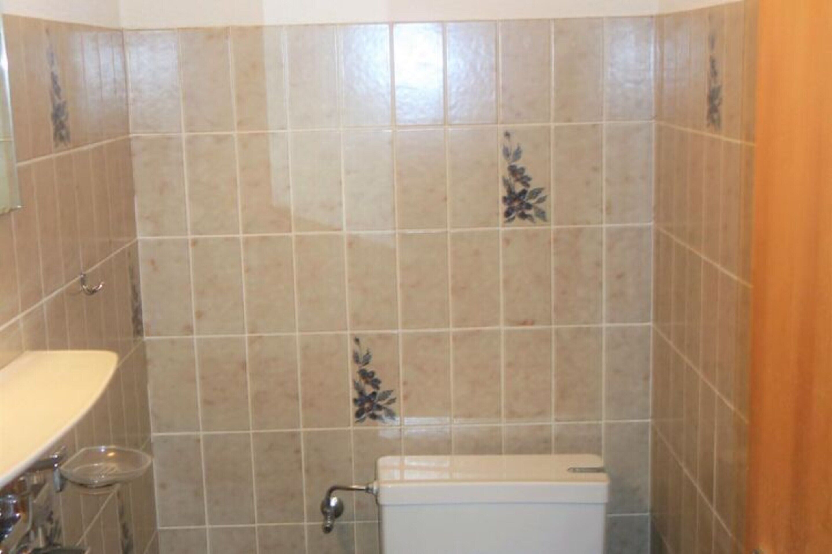 A bathroom with beige tiles, a toilet, and a sink.