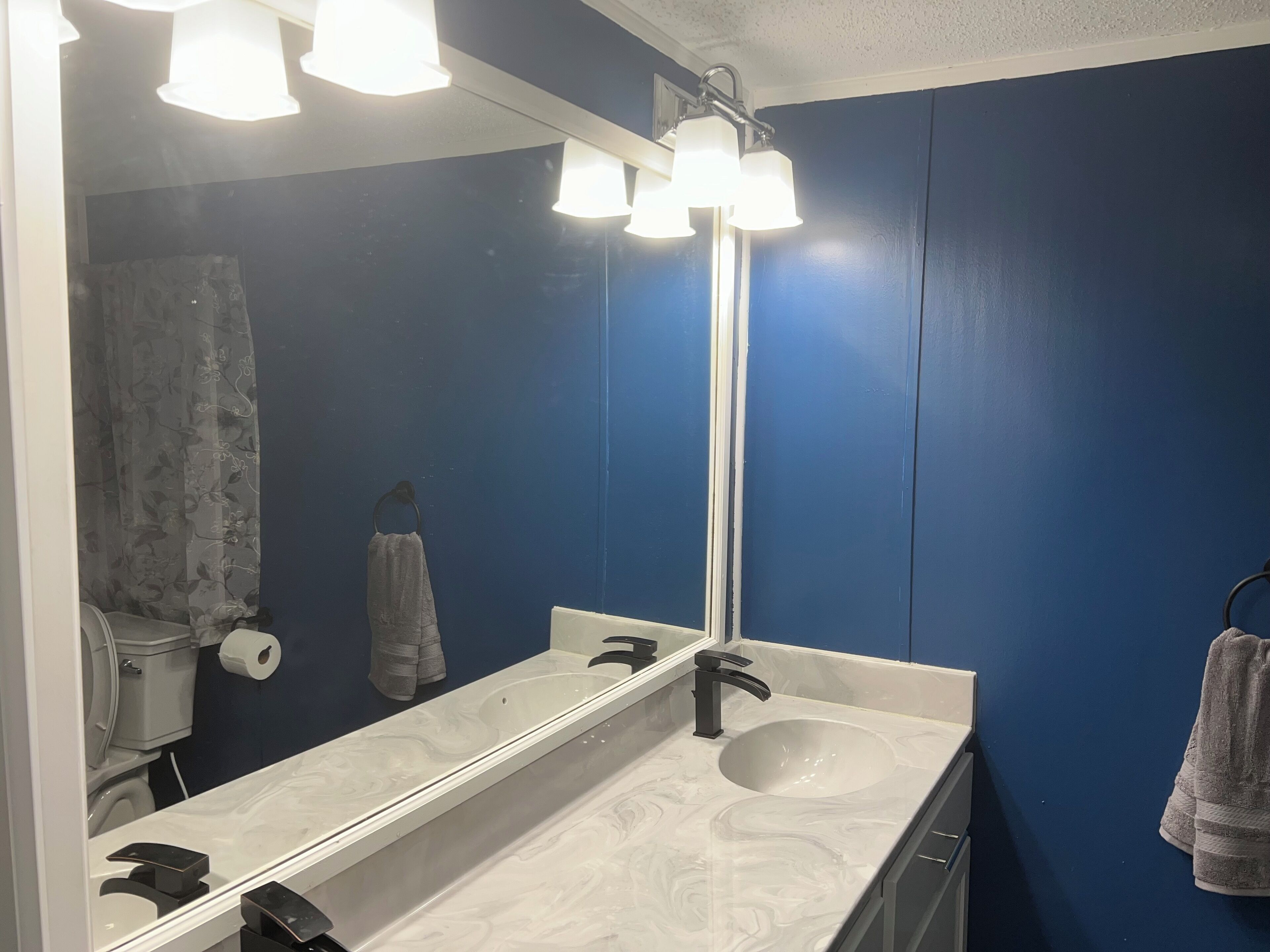 Un bagno con un lavandino bianco, uno specchio e un porta asciugamani.