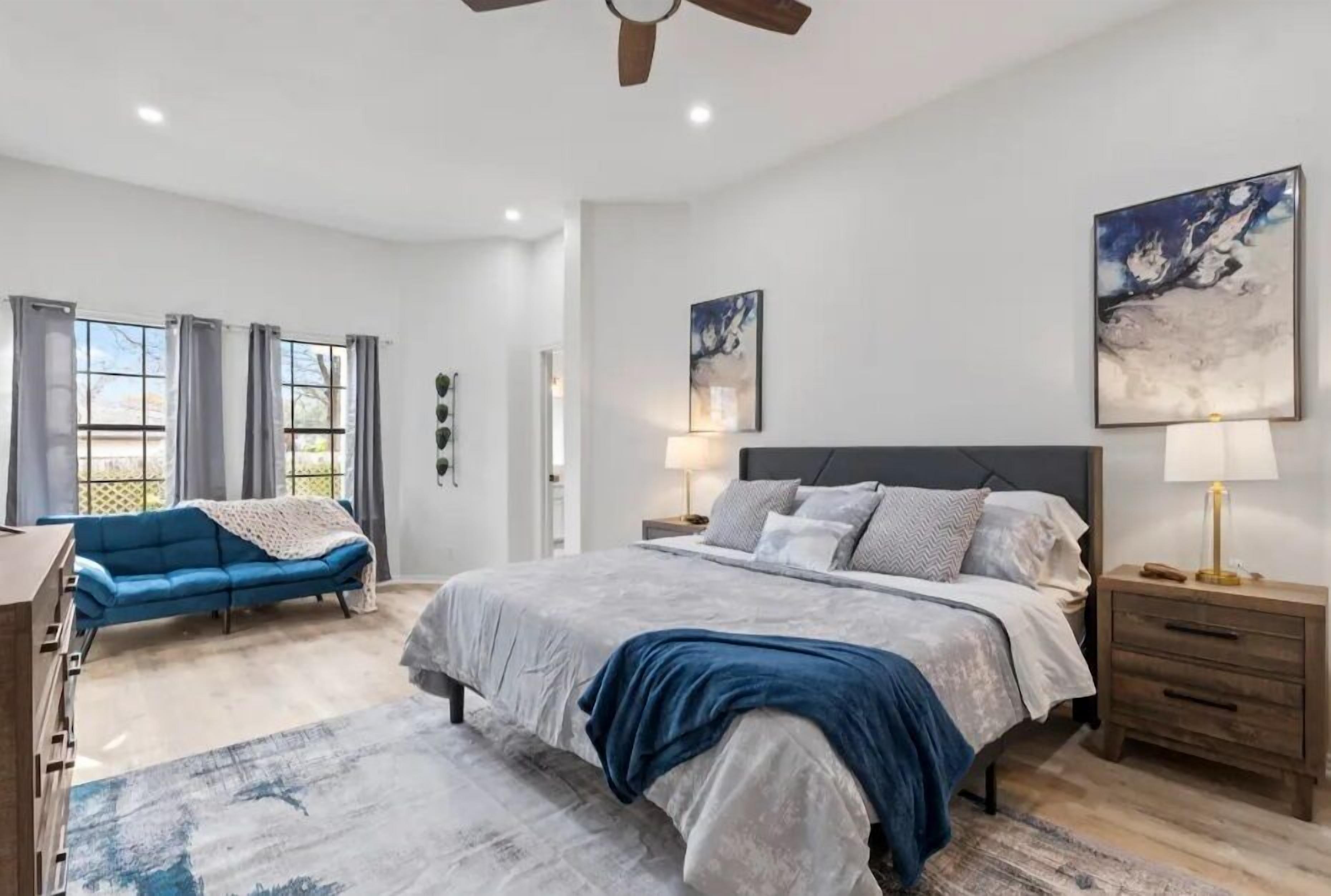 Une chambre à coucher avec un grand lit, un canapé bleu et un ventilateur de plafond.