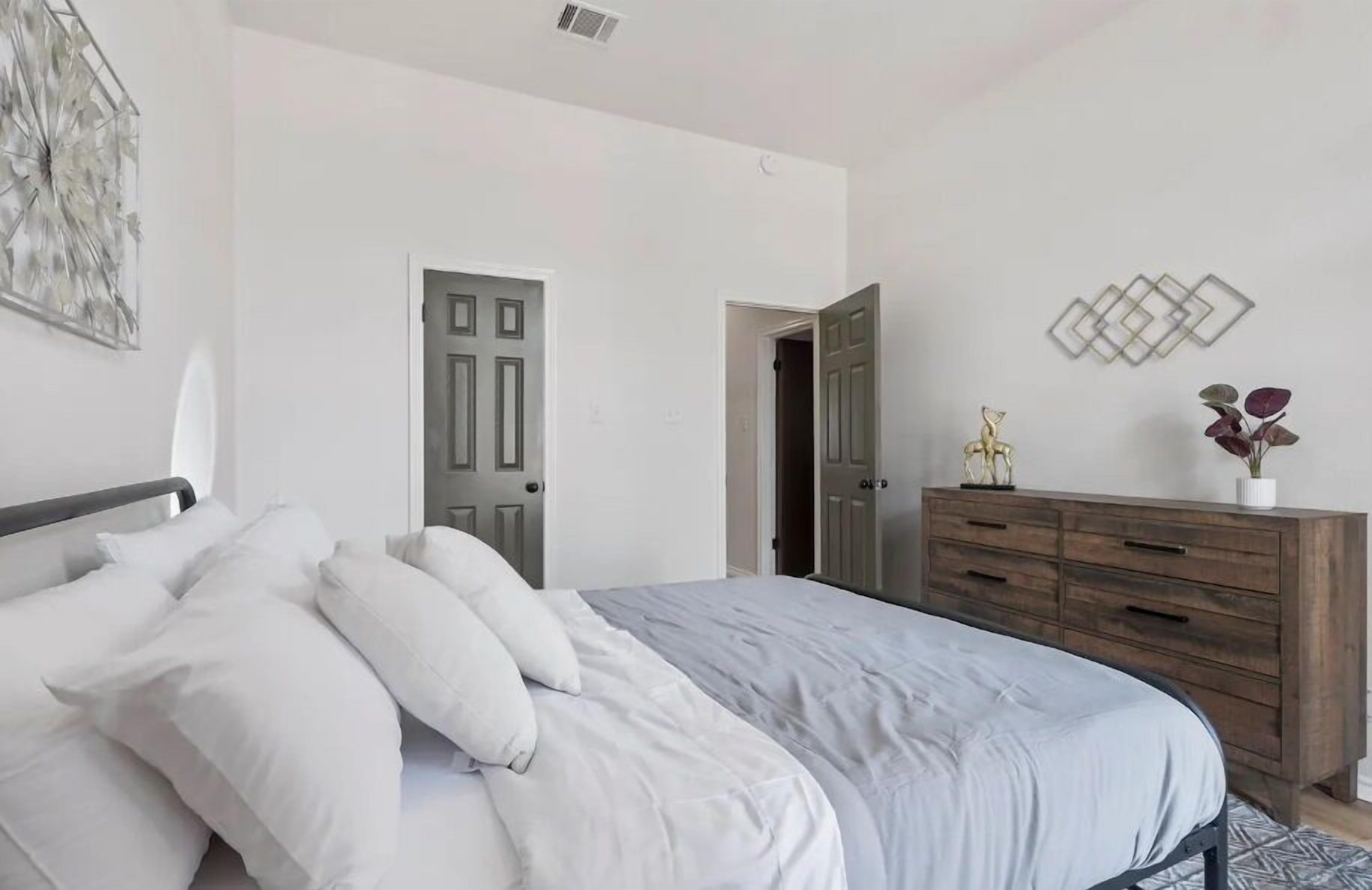 A bedroom with a bed, a dresser, and a door.