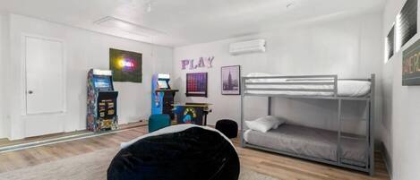 A modern bedroom with a bunk bed, a bean bag chair, a gaming console, and a wall with the word "PLAY".