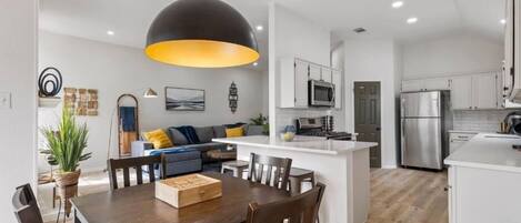 Una cocina moderna con gabinetes blancos, una isla central y electrodomésticos de acero inoxidable.
