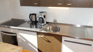 A modern kitchen with stainless steel appliances, a sink, and wooden cabinets.