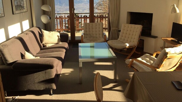 A living room with a sofa, two armchairs, a coffee table, and a TV.