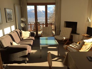 Un salon comprenant un canapé, deux fauteuils, une table basse et un téléviseur.