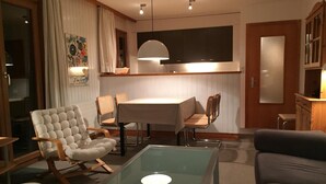 A modern living room with a glass coffee table, a sofa, and a dining area with a table and chairs.